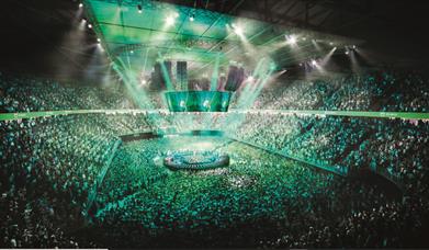full stadium with green lighting and central circular stage